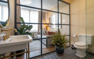 bathrooom separated from bed by a glass partition 